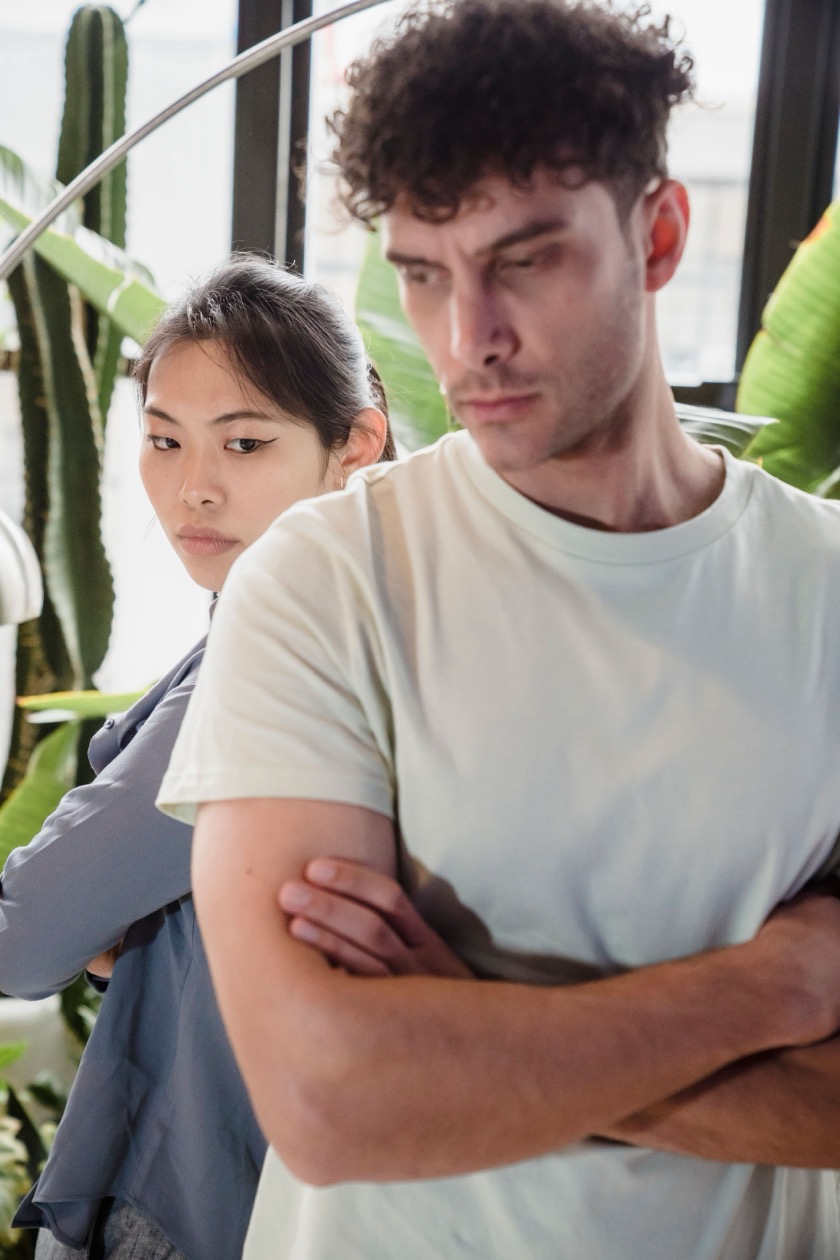 A couple standing back to back with arms crossed, emotionally distant