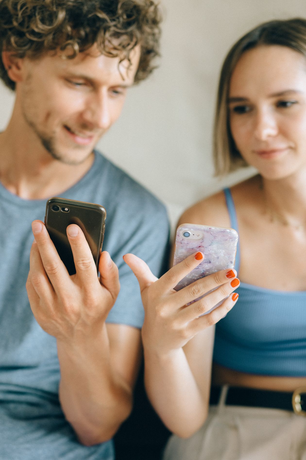 A couple sitting together, both looking at their phones