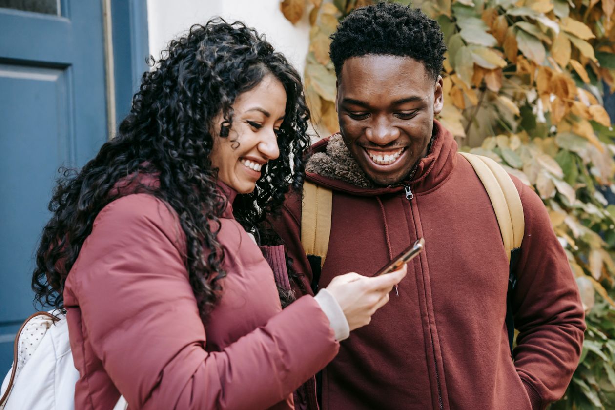 A couple smiling together while looking at a phone