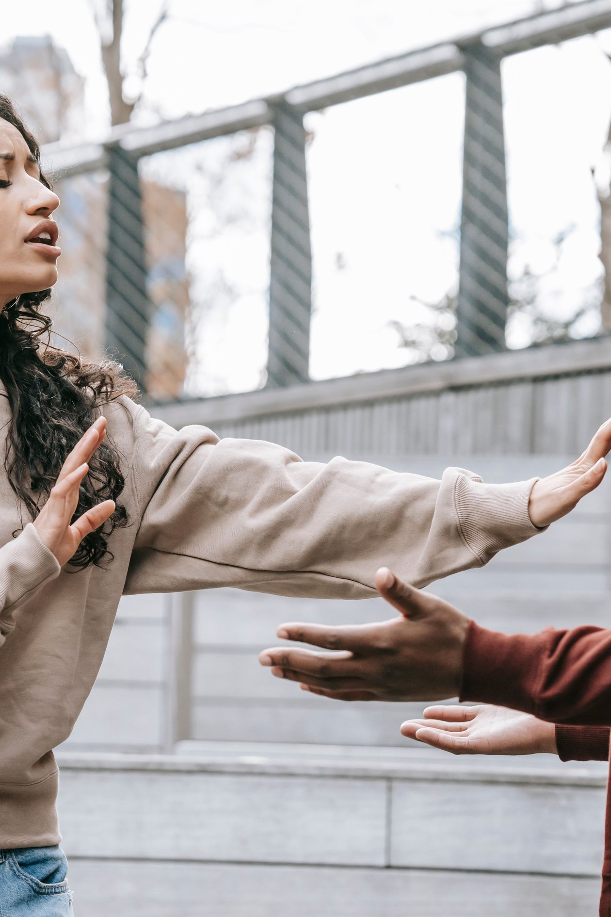 A woman reaching out with raised hands while her partner remains at a distance