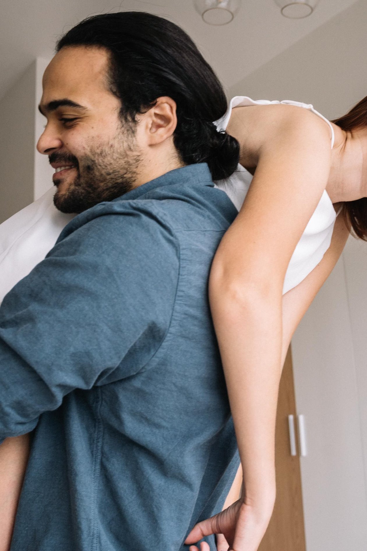 A couple laughing together playfully, one carrying the other