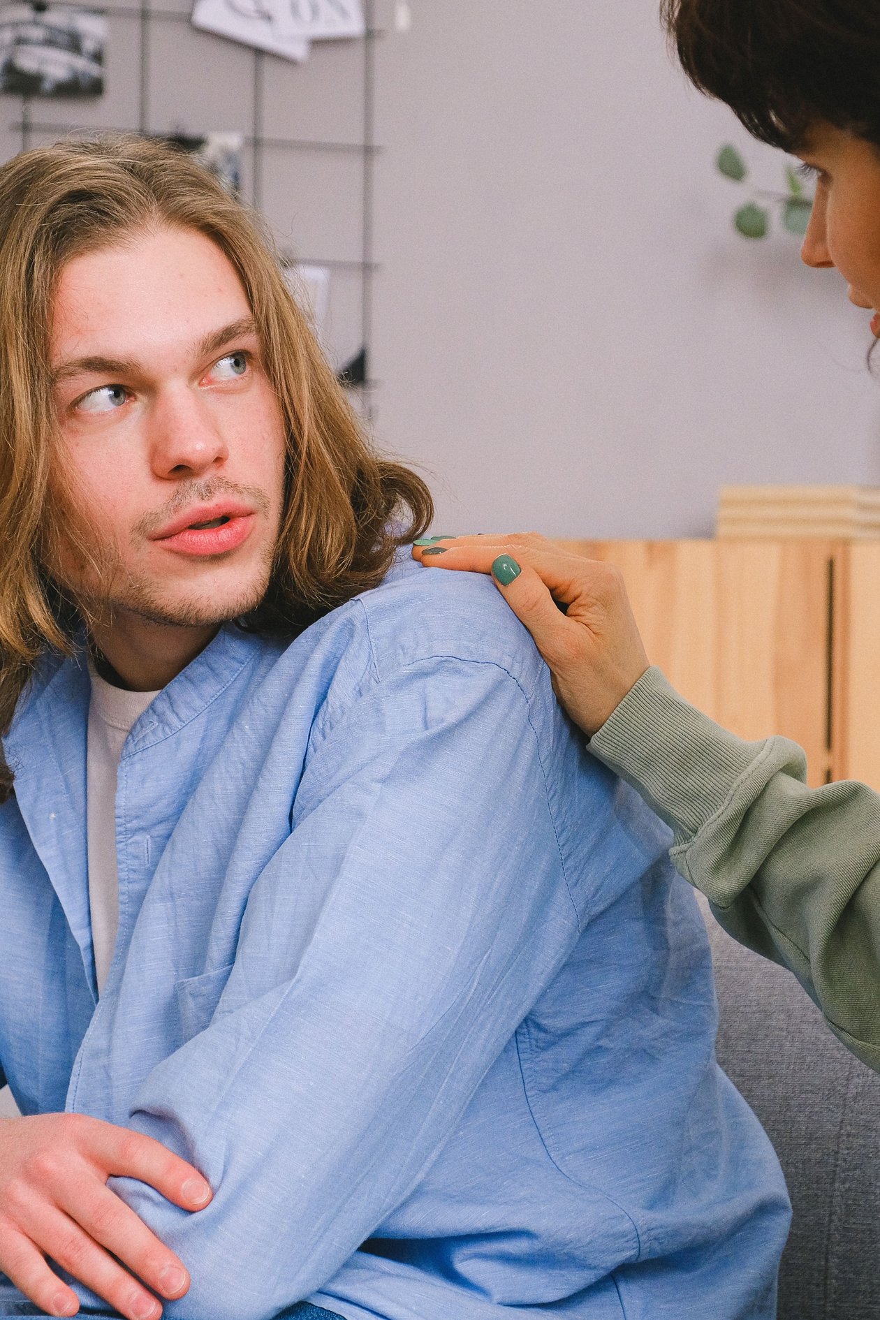 A woman gently touching her partner's shoulder while he looks back at her