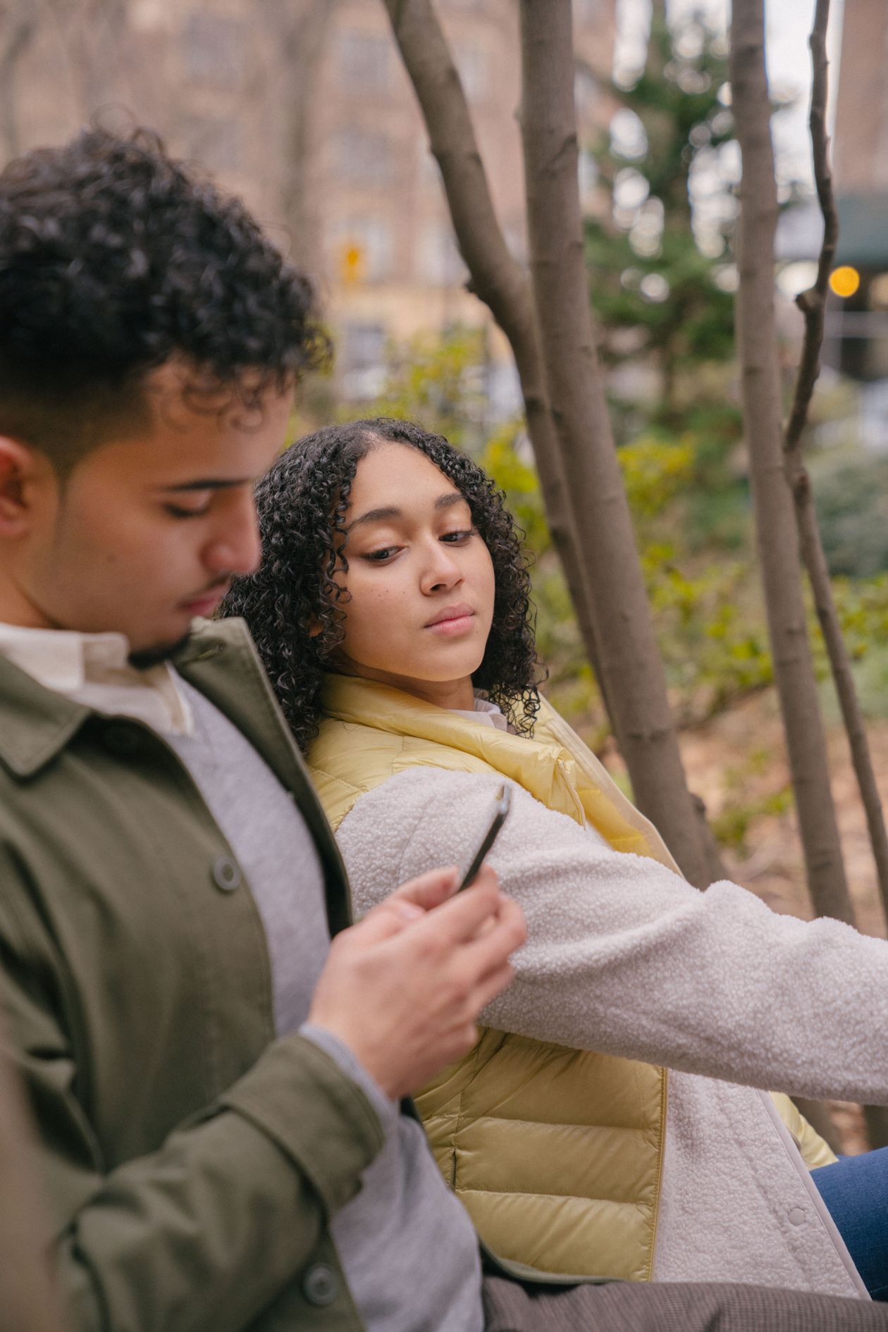 A man texting on his phone while his partner watches, tense