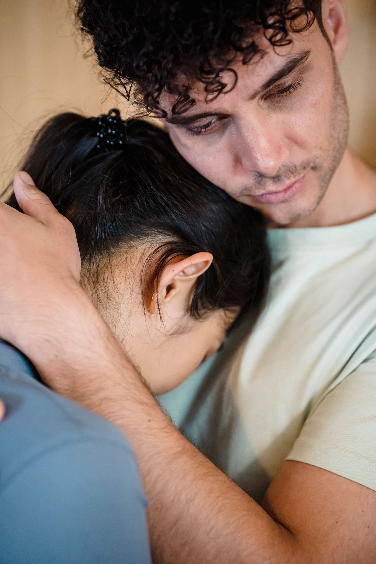 A man comforting his partner with a close, gentle embrace
