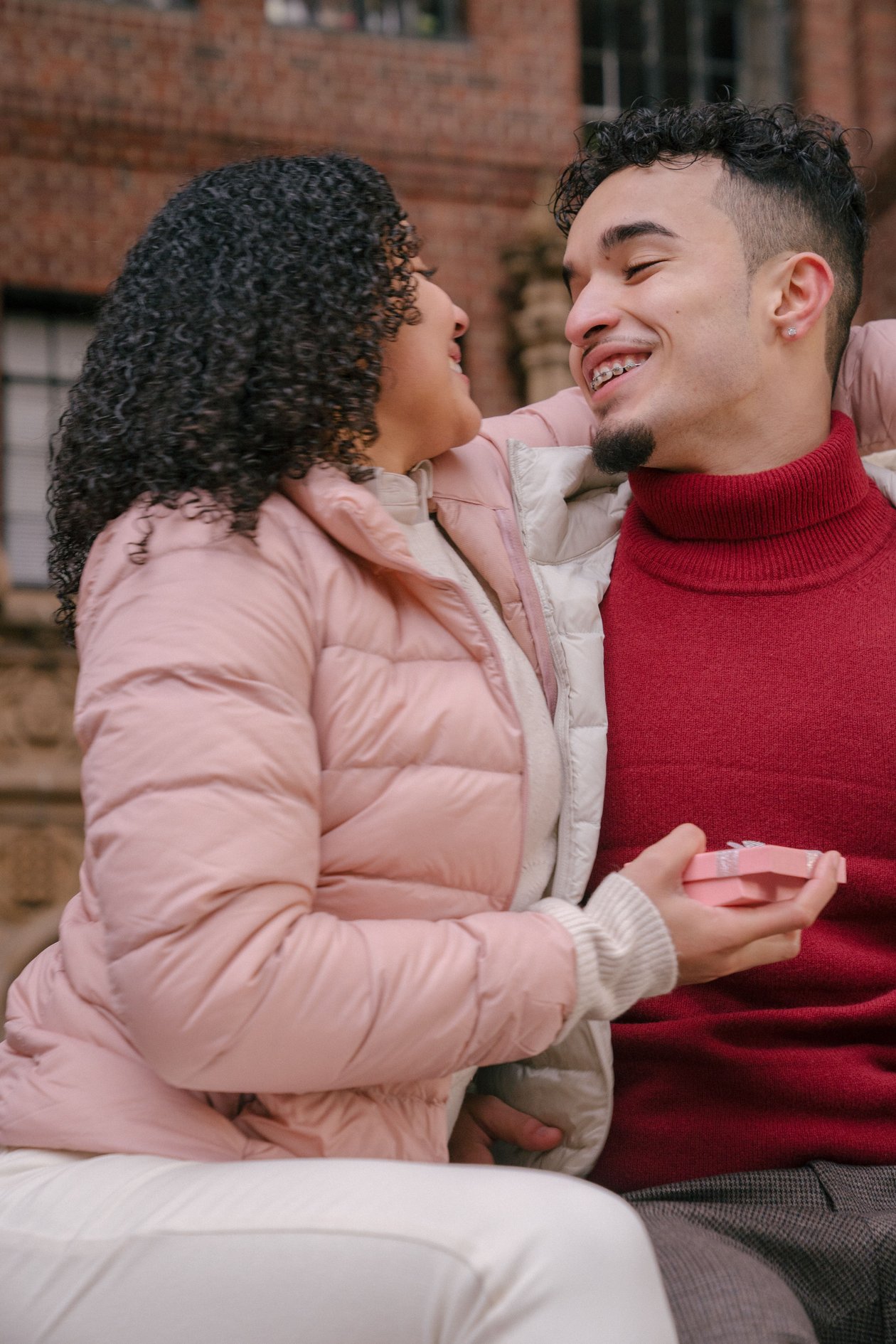 A couple exchanging a wrapped gift while smiling at each other