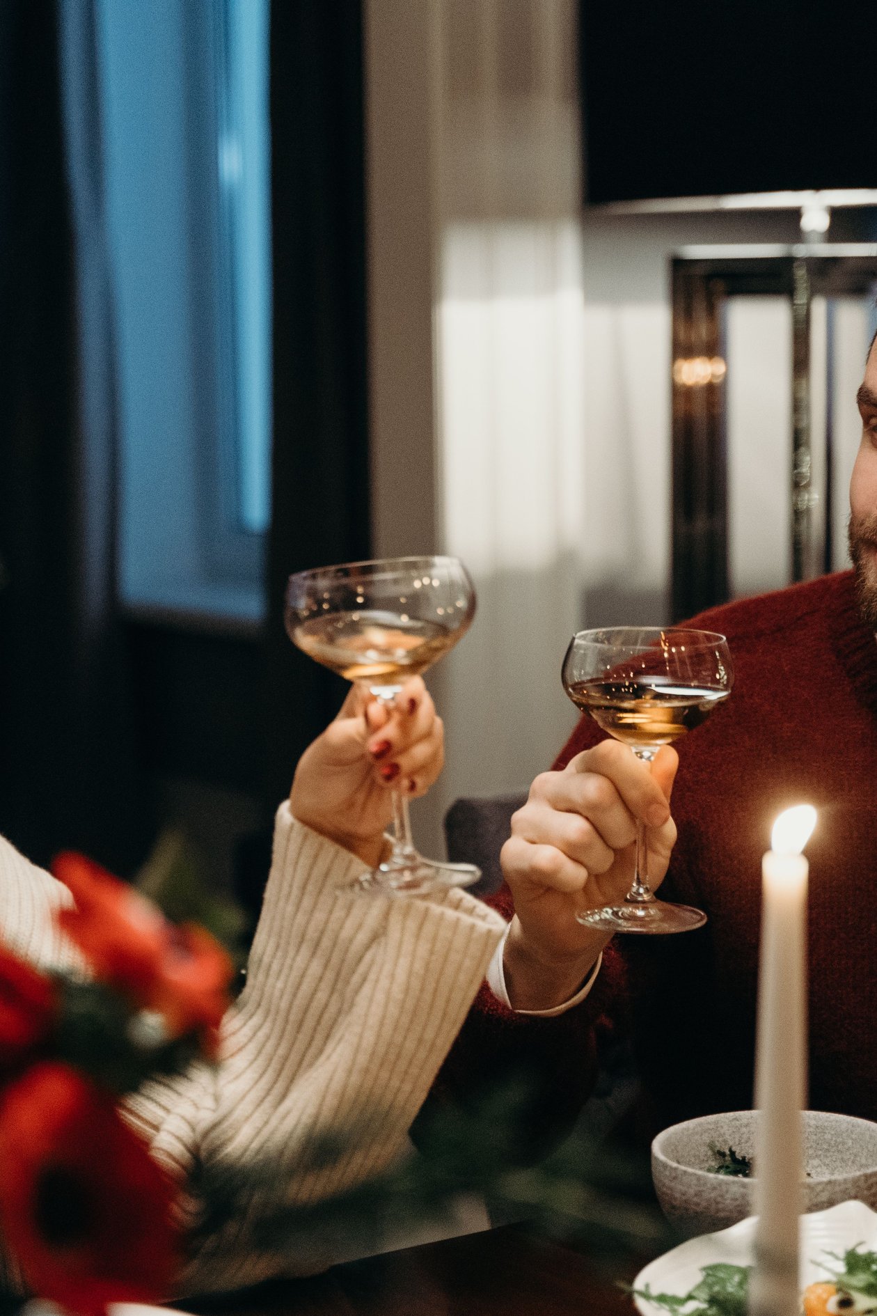 A couple toasting with wine glasses at a candlelit dinner